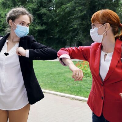 Twee vrouwen geven elkaar de ellebooggroet